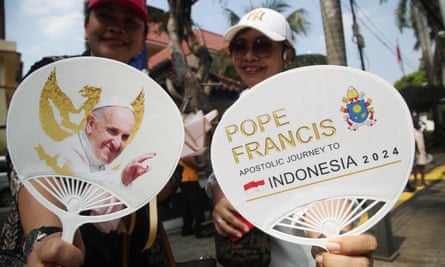 People hold fans commemorating Pope Francis’ visit as they gather outside the Indonesian Bishops’ Conference Headquarters in Jakarta.
