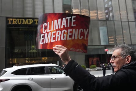 A man holds a sign that reads ‘climate emergency’.