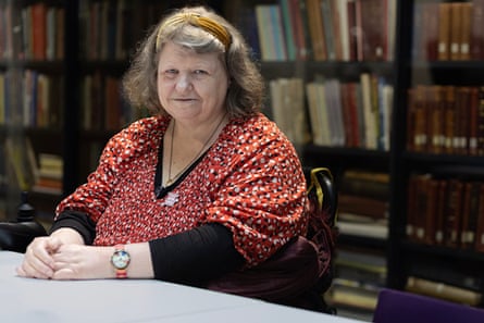 A woman in a floral red top sits at a desk.
