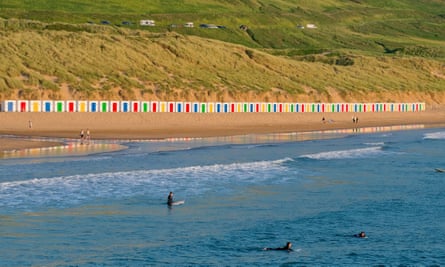 Saunton Sands beach with sand dunes and a line of colourful, painted beach huts on the beach in Devon