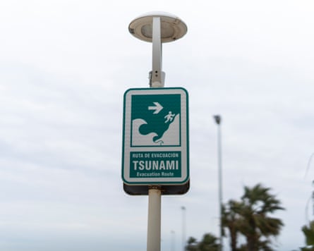 A sign on a lamppost says ‘tsunami evacuation route’ and has a picture of a person fleeing a wave to higher ground