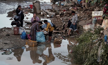 Over 200 Dead in Nepal Floods, Kathmandu Parts Submerged 3 People on phones and smoking and packing bags next to large pools of muddy water.