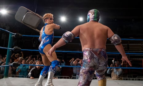 Garishly dressed wrestlers in the ring, one threatening the other with a fold-up chair