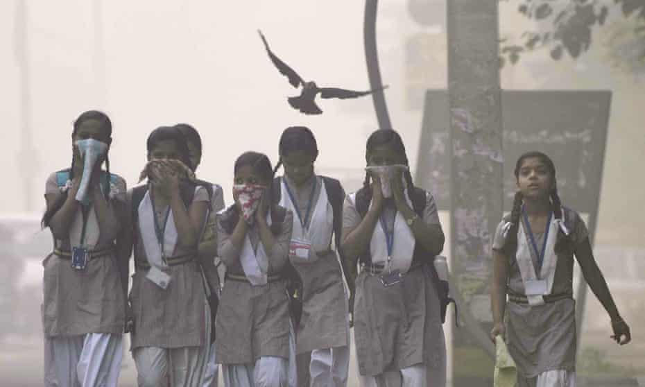 Children cover their face amid heavy smog in the early morning at Mayur Vihar, New Delhi, India