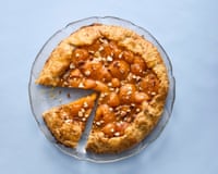 Felicity Cloake's apricot galette with a slice cut away, on a glass plate and light-blue background.