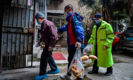 Community volunteers escort an elderly resident home in Wuhan earlier this month.