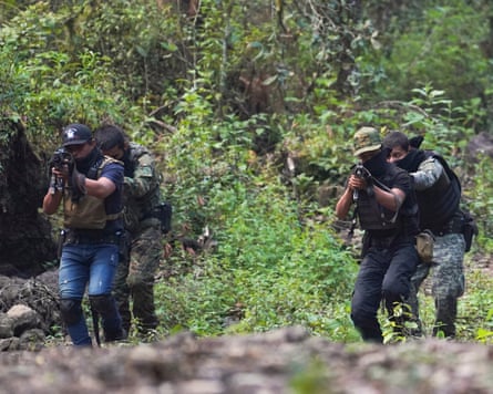 Men hold rifles while training in a wooded area