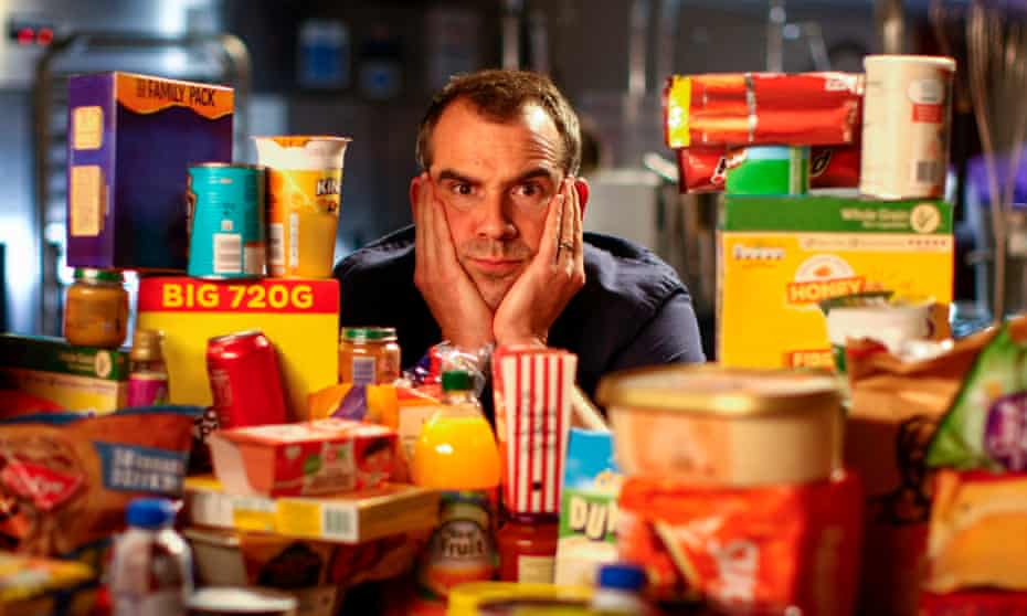 Dr Chris van Tulleken surrounded by an array of ultra-processed foods