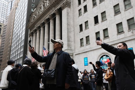 लोग आज न्यूयॉर्क स्टॉक एक्सचेंज के बाहर घूम रहे हैं, जहां सुबह के कारोबार में स्टॉक नीचे हैं क्योंकि मध्य पूर्व की घटनाओं से दुनिया भर के बाजारों में हलचल जारी है।