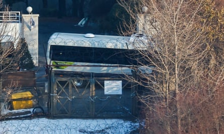 The light of a phone screen is seen through the windows of a minibus parked inside the compound of the fortified presidential residence