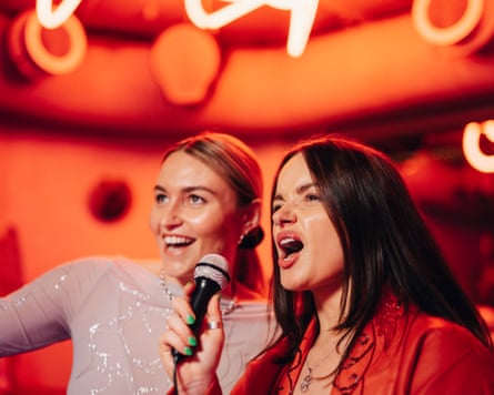 Passionate woman singing karaoke next to female friend at nightclub