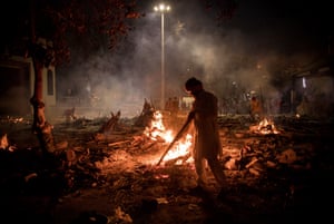 New Delhi, India: workers are seen at a crematorium where multiple funeral pyres are burning for people who died with Covid-19