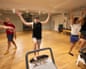 Sammy with his arms raised with one foot resting on a pilates machine