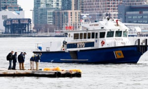 National Transportation Safety Board investigators and a New York City police boat on Monday, at the site where a helicopter crashed into the East River in New York, New York.