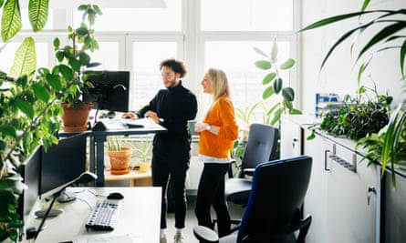 Two colleagues looking at a computer at a standing desk in a modern office space