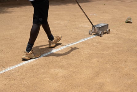 Coach David Tyaba marks a court in preparation for members to play at Makerere University Guest House Tennis Club.