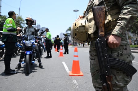 A Peruvian air force soldier stands guard as police officers search motorcyclists at a checkpoint
