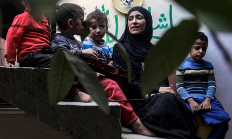 Palestinian musician Jawaher al-Aqraa sits with her violin next to children on a staircase in her home in Deir al-Balah in the central Gaza Strip
