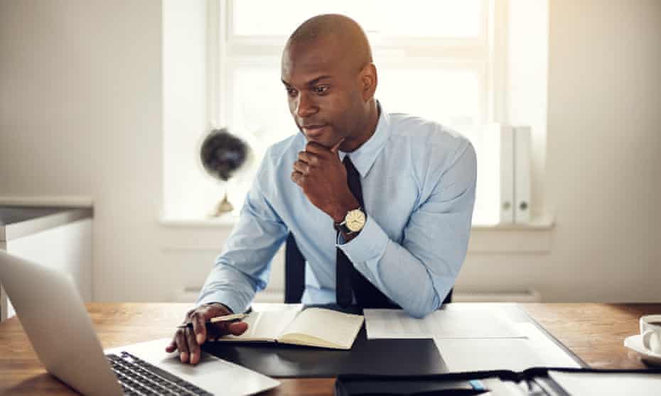 Young businessman working on a laptop in an officePosed by Model Man working from home GettyImages-753288541 Young business executive wearing a shirt and tie sitting at his desk in an office working online with a laptop