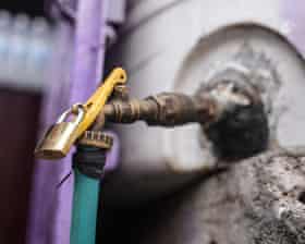 A padlock secures a brass outdoor water tap in Taiz