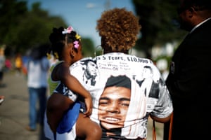 A spectator holds her child as the funeral procession takes p[lace