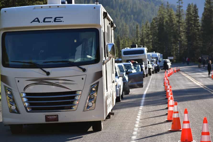 Cars, trucks and recreational vehicles line up next to a row of cones at Yellowstone’s entrance.