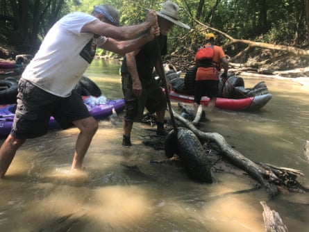 a man digging a tire out from under a tree branch in a river