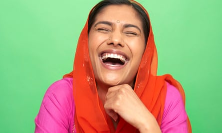 Portrait of woman with red head scarf on laughing, against green background.