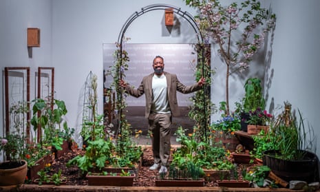 Jason Williams stands in an archway. In front of him is  display of flowerbeds and plant pots laid out in a small area.