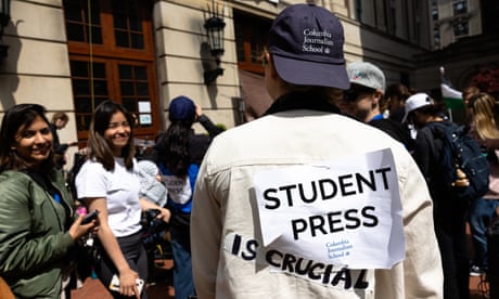 a person wearing a Columbia journalism hat and a sign saying 'Student press'
