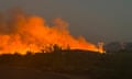 An image that is half black earth, half bright orange flames and gray smoke.