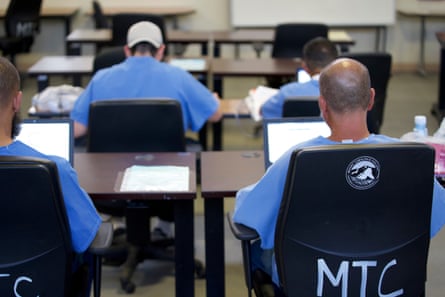 Men in blue prison outfits sitting in chair labeled MTC