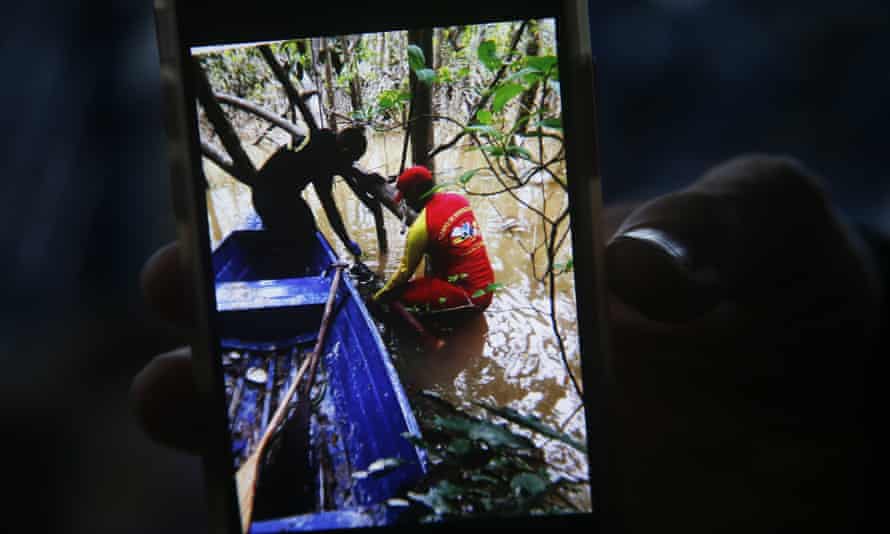 A firefighter holds a phone with a picture showing the moment a backpack was found during a search for Indigenous expert Bruno Pereira and British journalist Dom Phillips