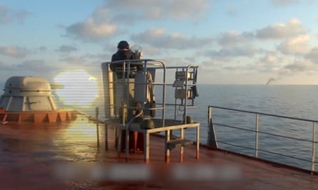 Still from video showing guns being fired from ship’s deck