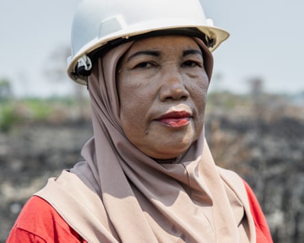 A female firefighter poses for a portrait on burned peatland