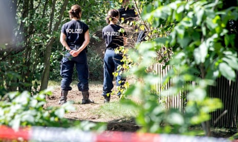 Police stand guard during a search in a garden allotment in Hanover, where the latest suspect lives.