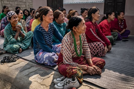 A group of Nepali village women sit on the floor to listen to a talk