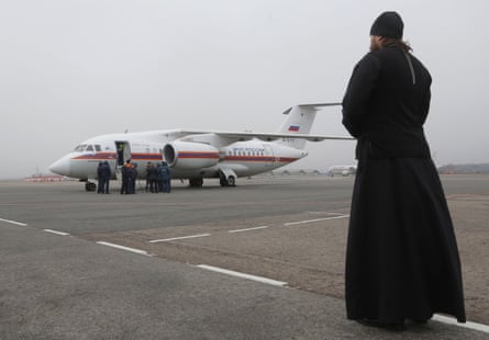 An Orthodox priest watches as the bodies of the crash victims arrive in St Petersburg.