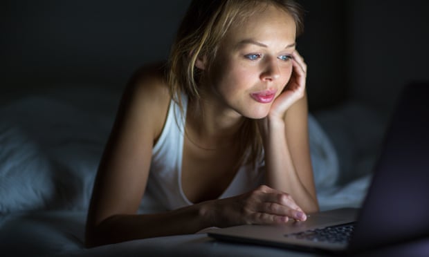 Woman using laptop in bed (posed by model)