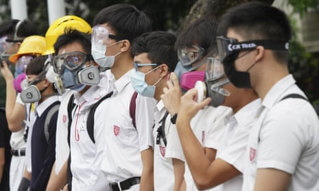 Students wearing gas masks and helmets hold a rally outside Queen’s College, in Hong Kong.