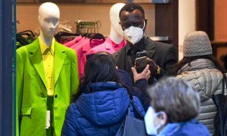 A security officer checks customers’ green pass at the entrance to a clothing store in Naples, southern Italy, 01 February 2022.