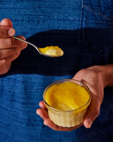 Two hands hold a ramekin and spoon with a creamy dessert inside.