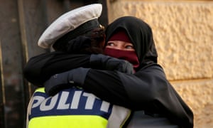 Ayah, a niqab wearer weeps as she is embraced by a police officer during a demonstration against the Danish face veil ban in Copenhagen.