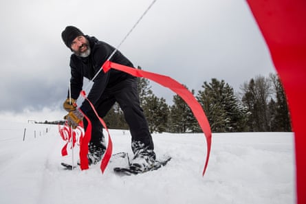 Man in snow holding line with red ribbons hanging from it