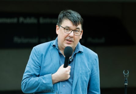 A man in a blue suit speaks into a microphone.