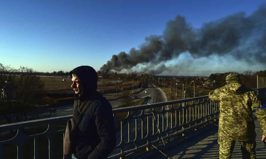 A Ukrainian soldier watches as a cloud of smoke rises after an explosion near the airport in Lviv on Friday.