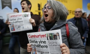Protesters shout slogans as they hold the latest copy of Cumhuriyet outside its headquarters