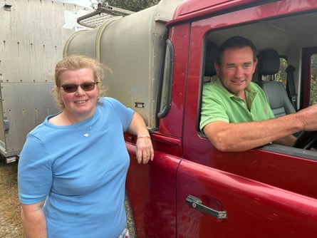 A man sits in a vehicle cab, a woman stands beside him