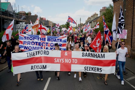 A large group of people carry flags and banners down a residential street