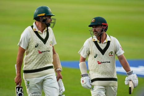 Cricketers Scott Boland and Travis Head walk off the field together, conversing